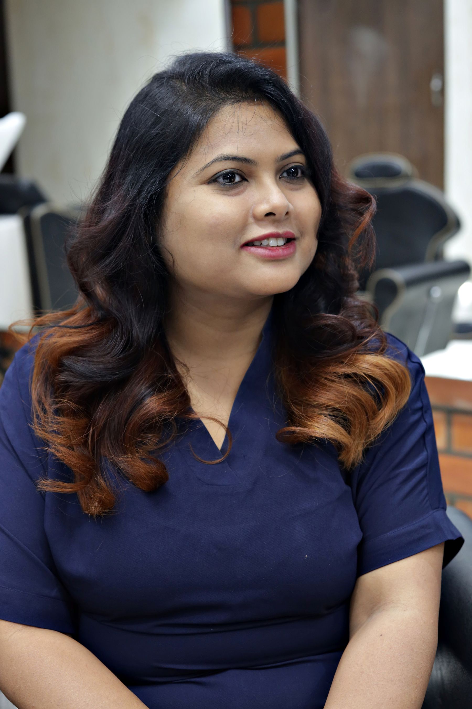 Smiling woman with long styled curls in a salon chair